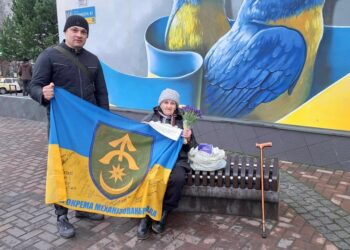 Пенсіонерка Наталя Марюхно передає зібрані від читання віршів гроші волонтеру Сергію Окуню. Фото: надане волонтером.